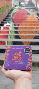 Nuestro Chocolate de Mesa 60% cacao combina la fuerza del grano de Rionegro, Santander, con la suavidad de la lecitina de soya y el dulzor equilibrado del azúcar. Es un chocolate auténtico, pensado para compartir en taza, que conserva la tradición artesanal y el poder energético del cacao colombiano.  🌈 El empaque también cuenta una historia Su diseño en morado y craquelado naranja refleja la esencia del cacao:  El morado, símbolo del inicio de la fermentación, cuando el grano comienza a transformarse en chocolate.  El naranja craquelado, inspirado en figuras ancestrales, representa la herencia cultural y el arte de convertir el cacao en alimento sagrado.  Cada tableta de 250g es un viaje a las raíces del cacao, una experiencia donde tradición y sabor se unen en cada taza de chocolate.